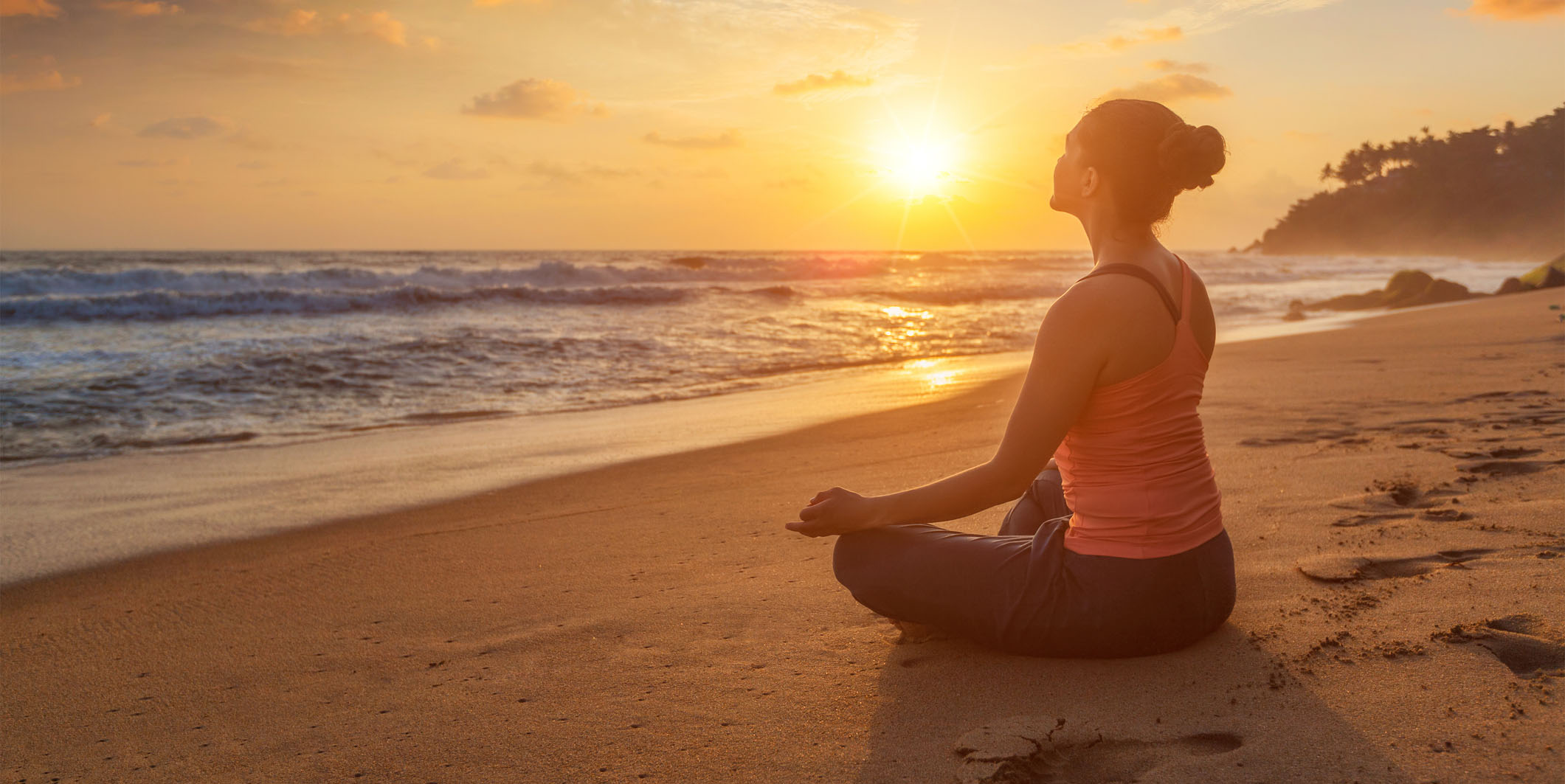 Woman doing yoga outdoors at beach - Padmasana lotus pose